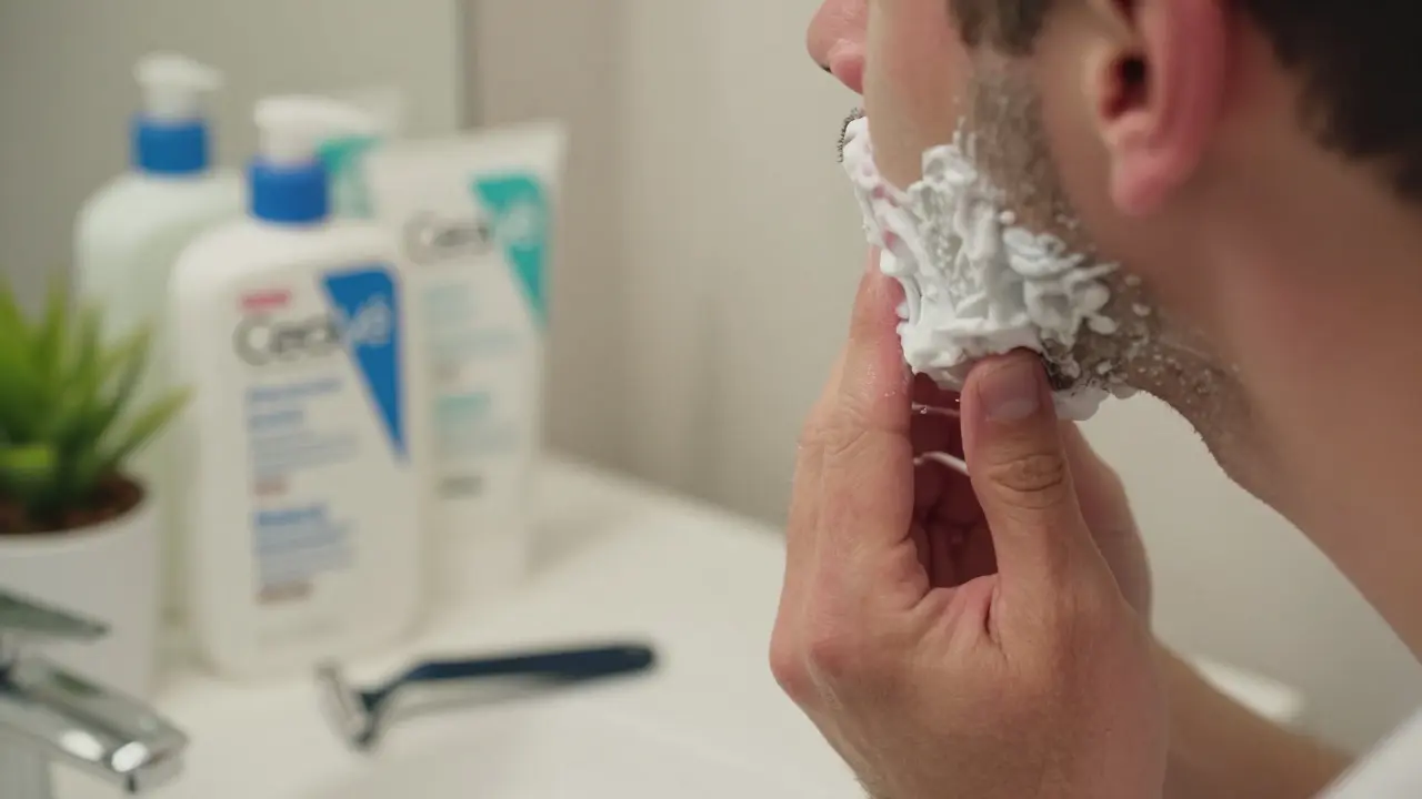 Muž aplikuje CeraVe čisticí gel po holení, s mírně červenou pokožkou a holením na pozadí.